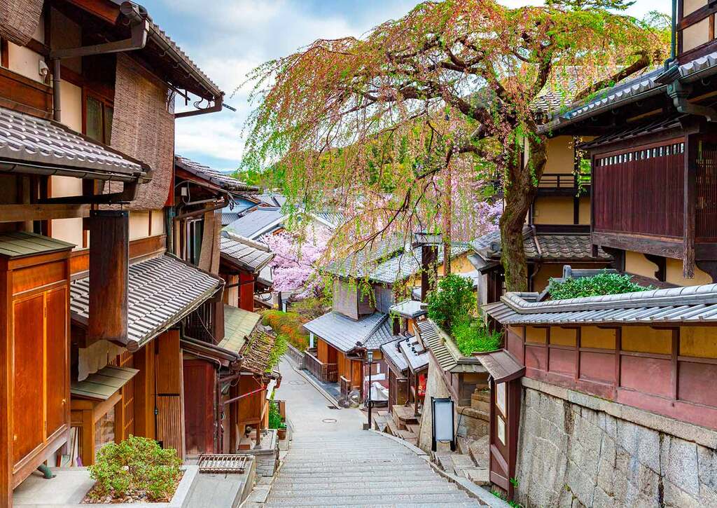Stepped stone lane in Higashiyama lined with traditional wooden machiya and spring blossoms