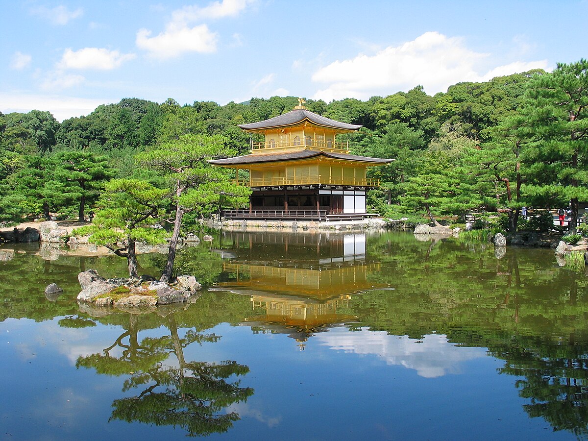 Kinkaku-ji Golden Pavilion reflecting on a still pond surrounded by pines