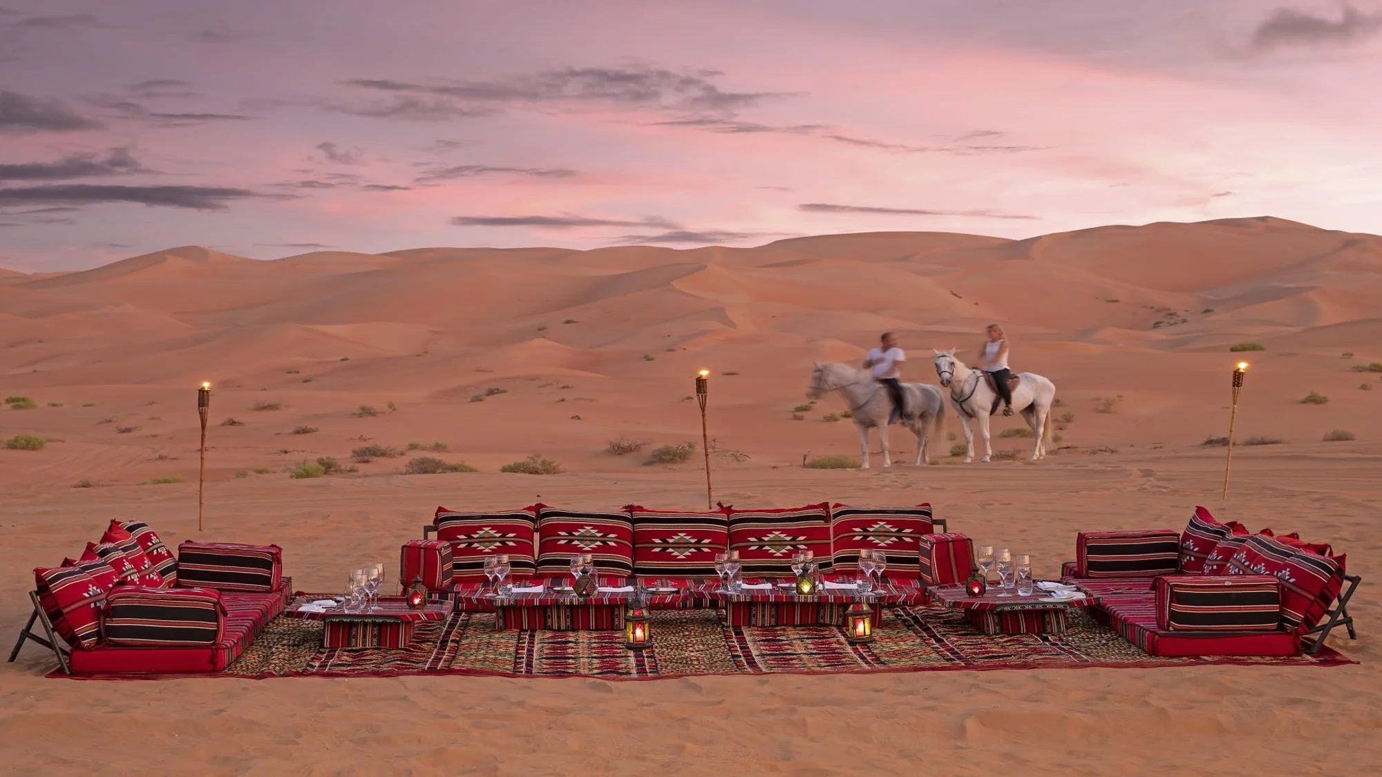 Desert camp with traditional majlis tents and horses.