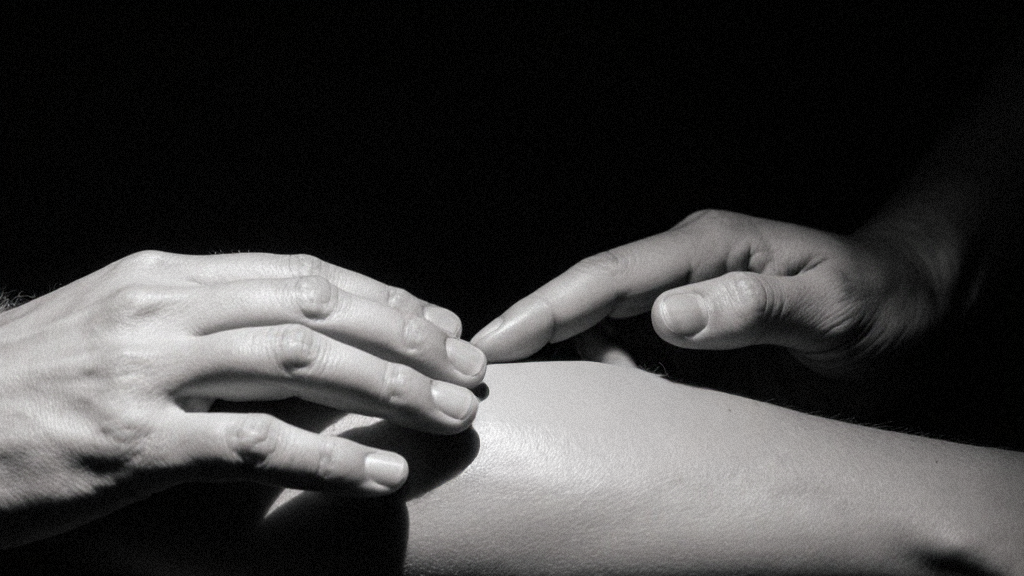 Hands gently exploring fascia and connective tissue on forearm, intimate detail of touch and awareness