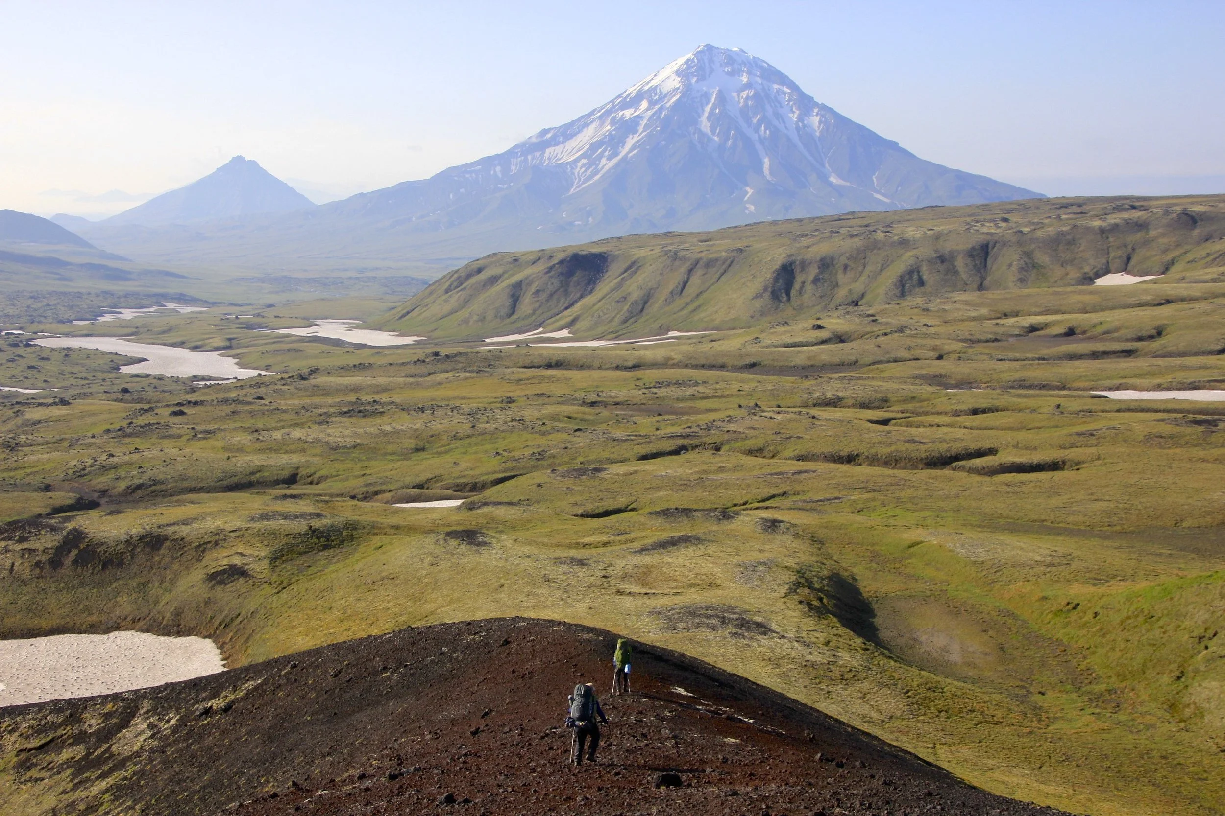 Sweeping tundra and cinder cones with a solitary volcano on the horizon.