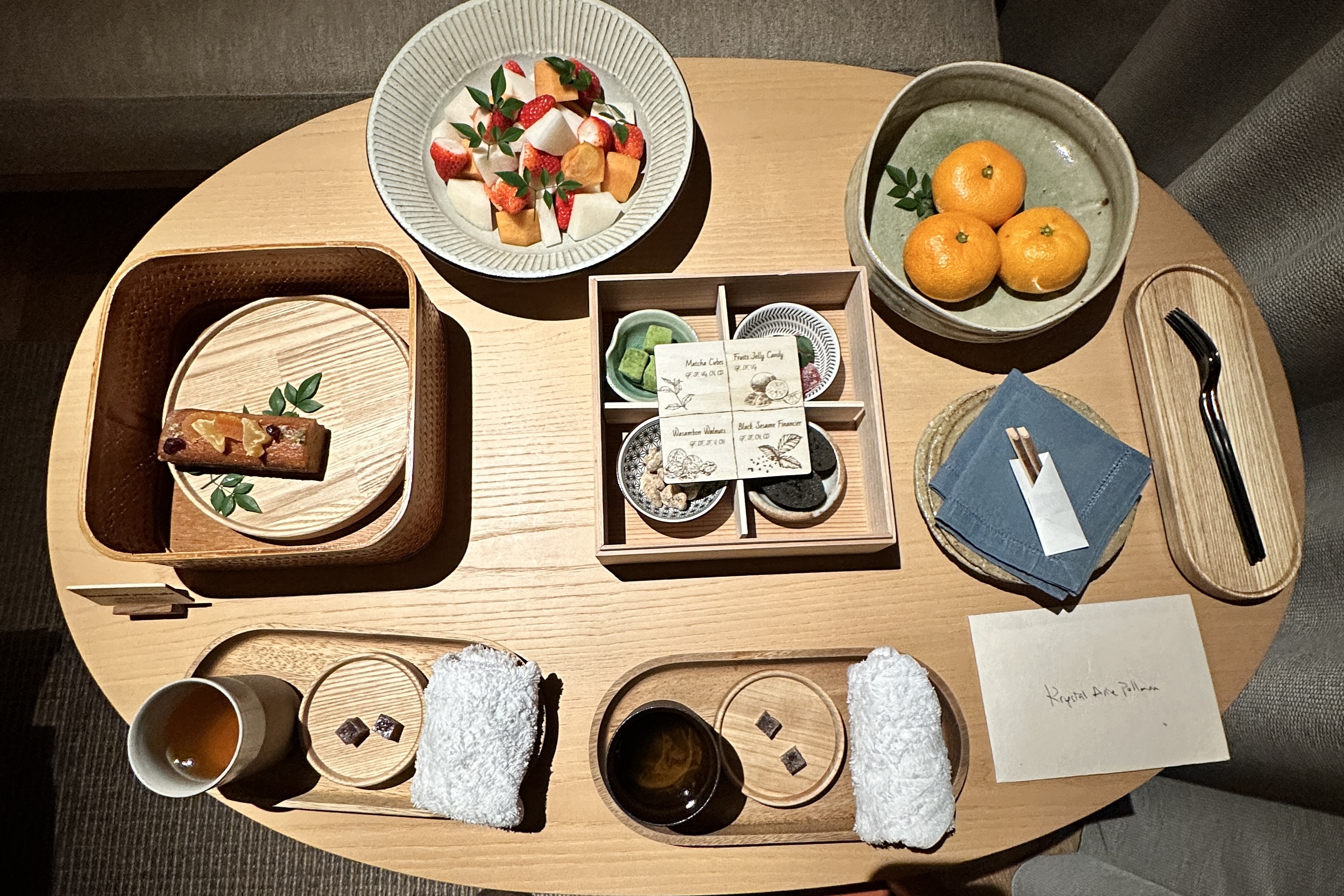 Close-up of the in-room welcome treats, fruit, yuzu cake, matcha squares, walnuts, black sesamie financier.