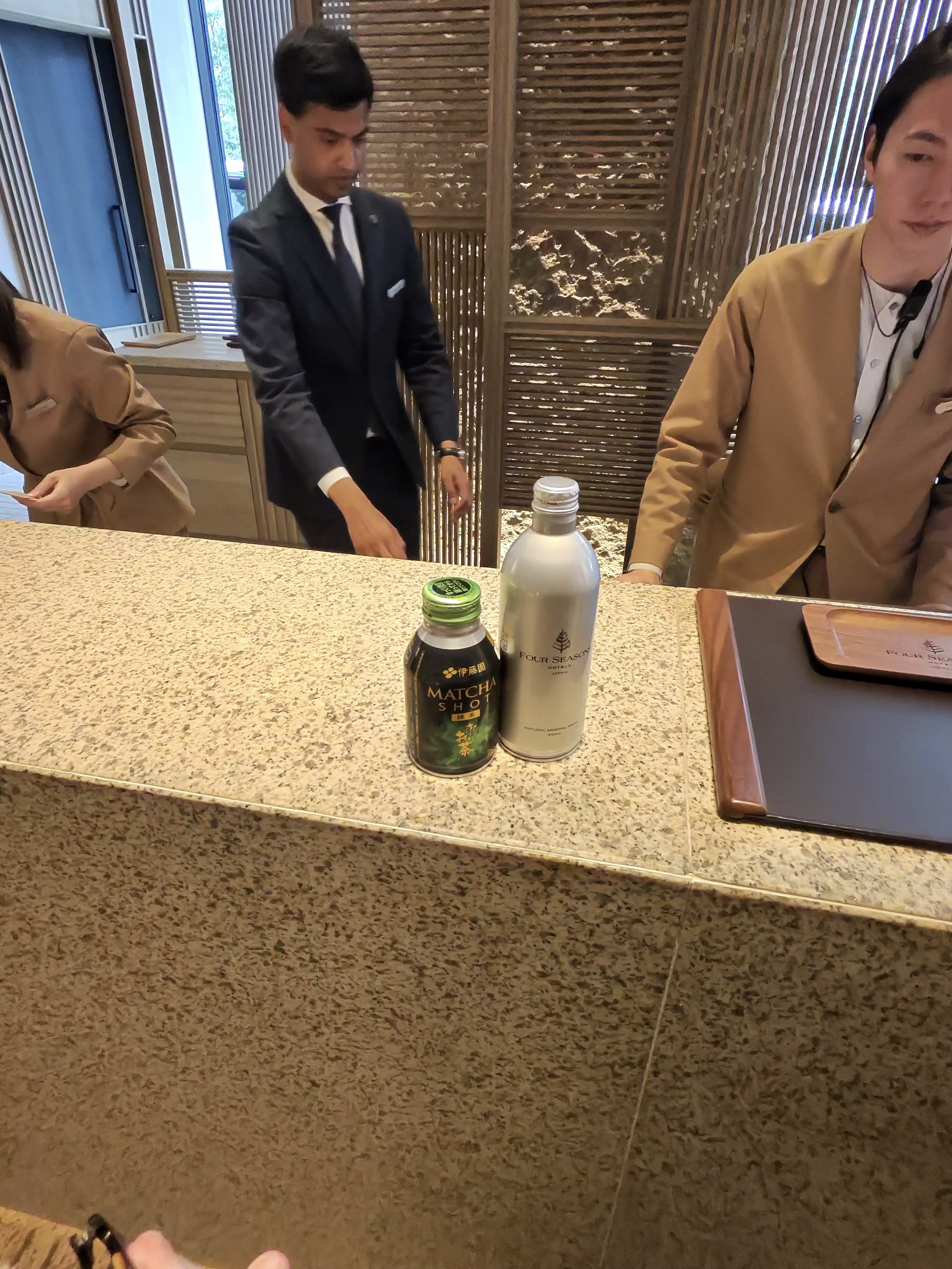 The front desk with a matcha and water welcome drink at the Four Seasons Osaka.