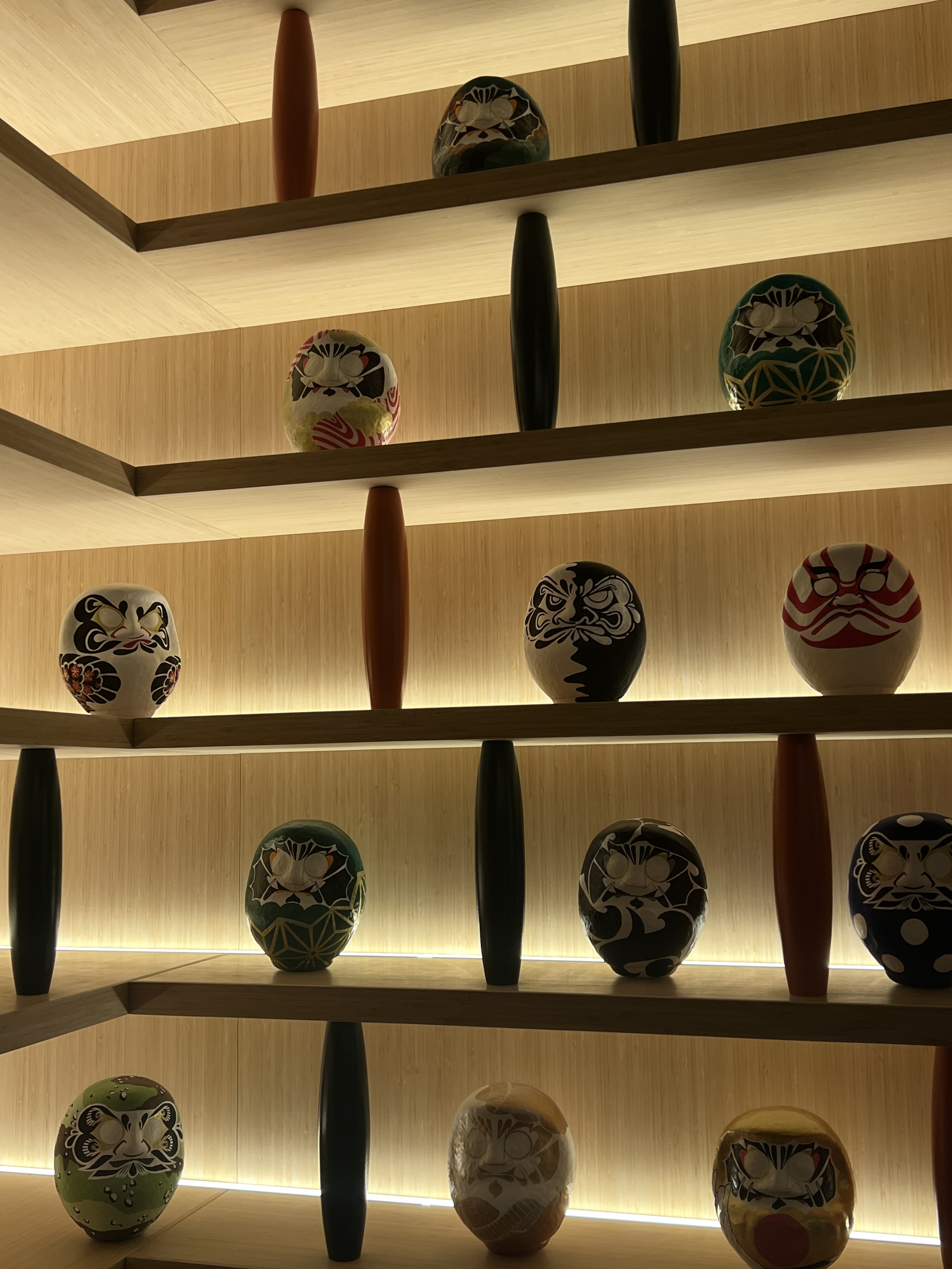 A wall with shelves holding various daruma