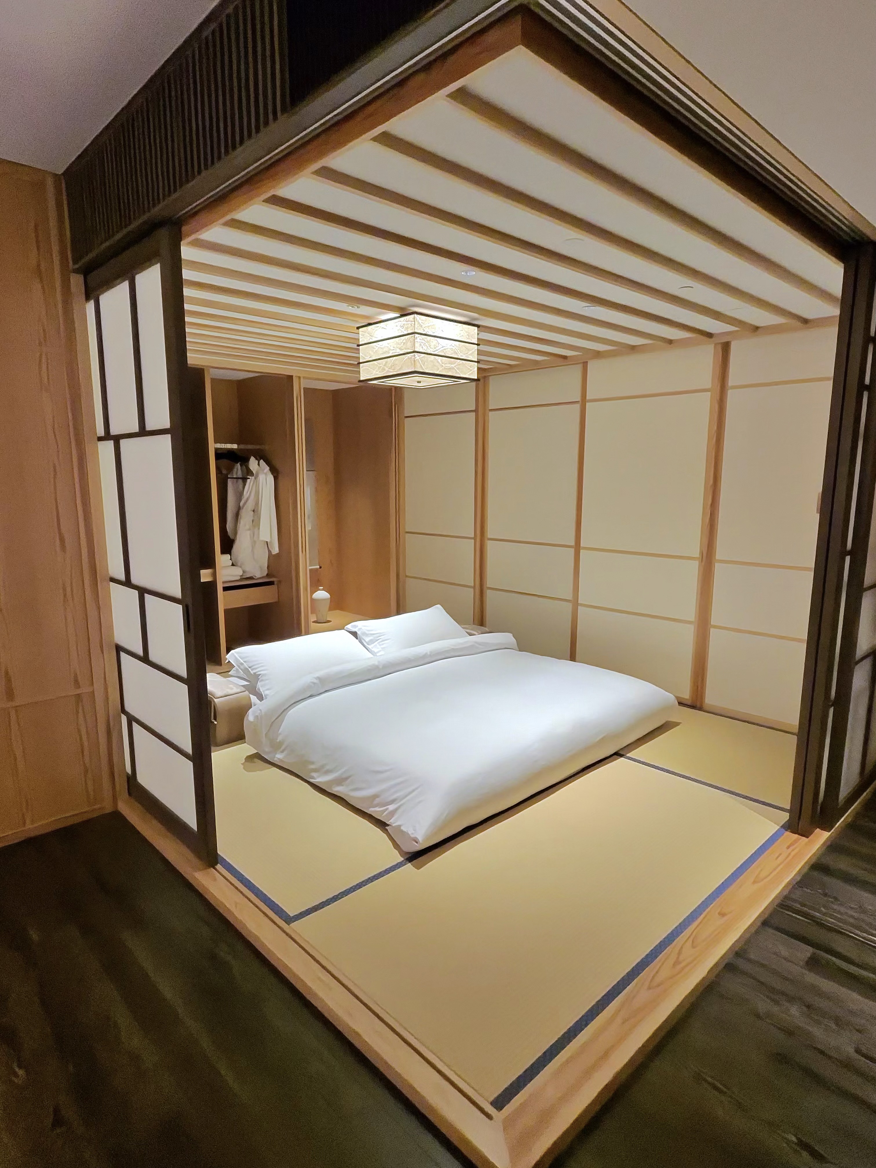 Tatami-floored bedroom in the two-bedroom residence at Four Seasons Kyoto, with a low platform bed, shoji screens, and a traditional paper lantern overhead.