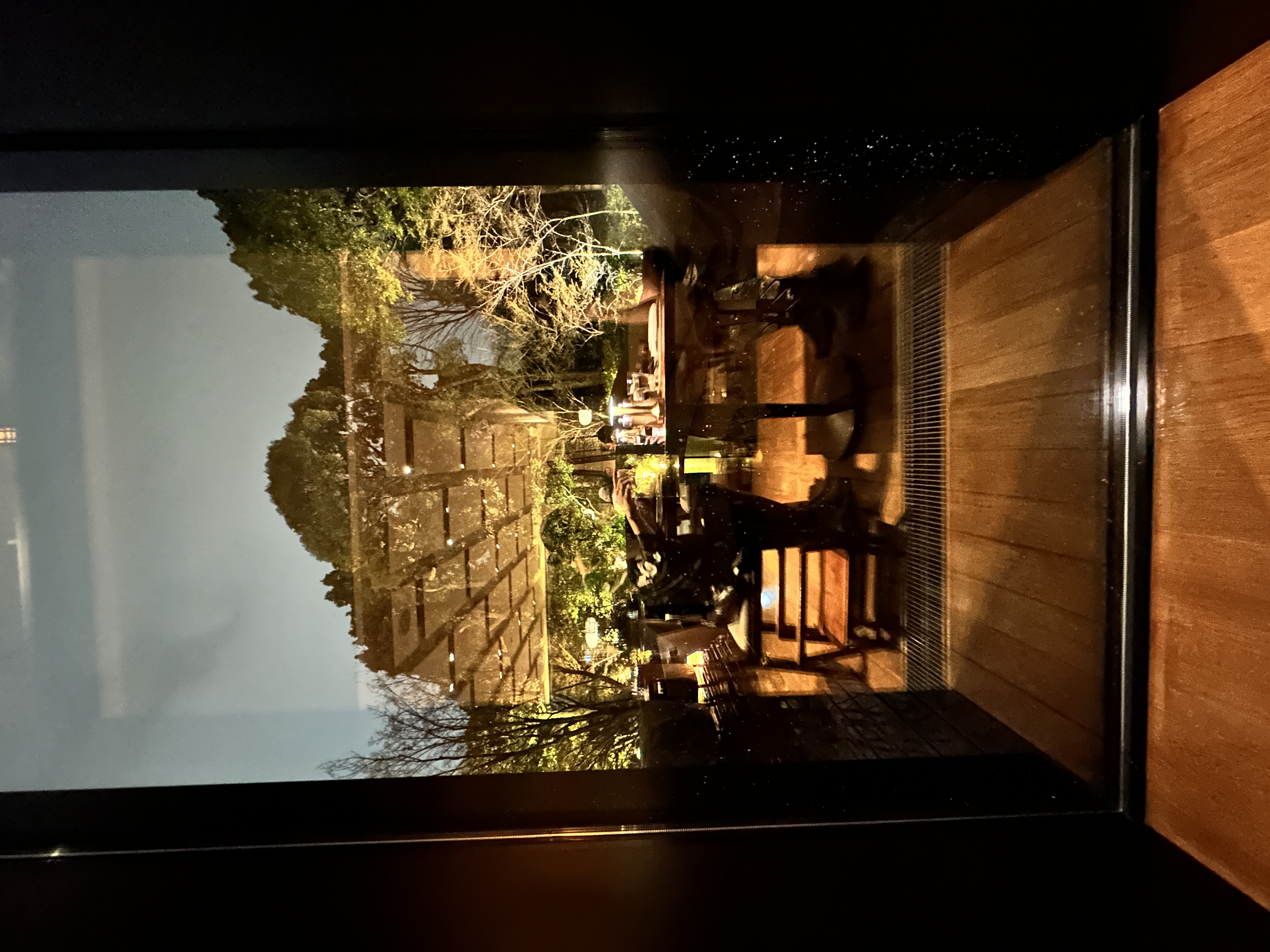 The Four Seasons Kyoto garden lit up at night, reflected in the restaurant window.