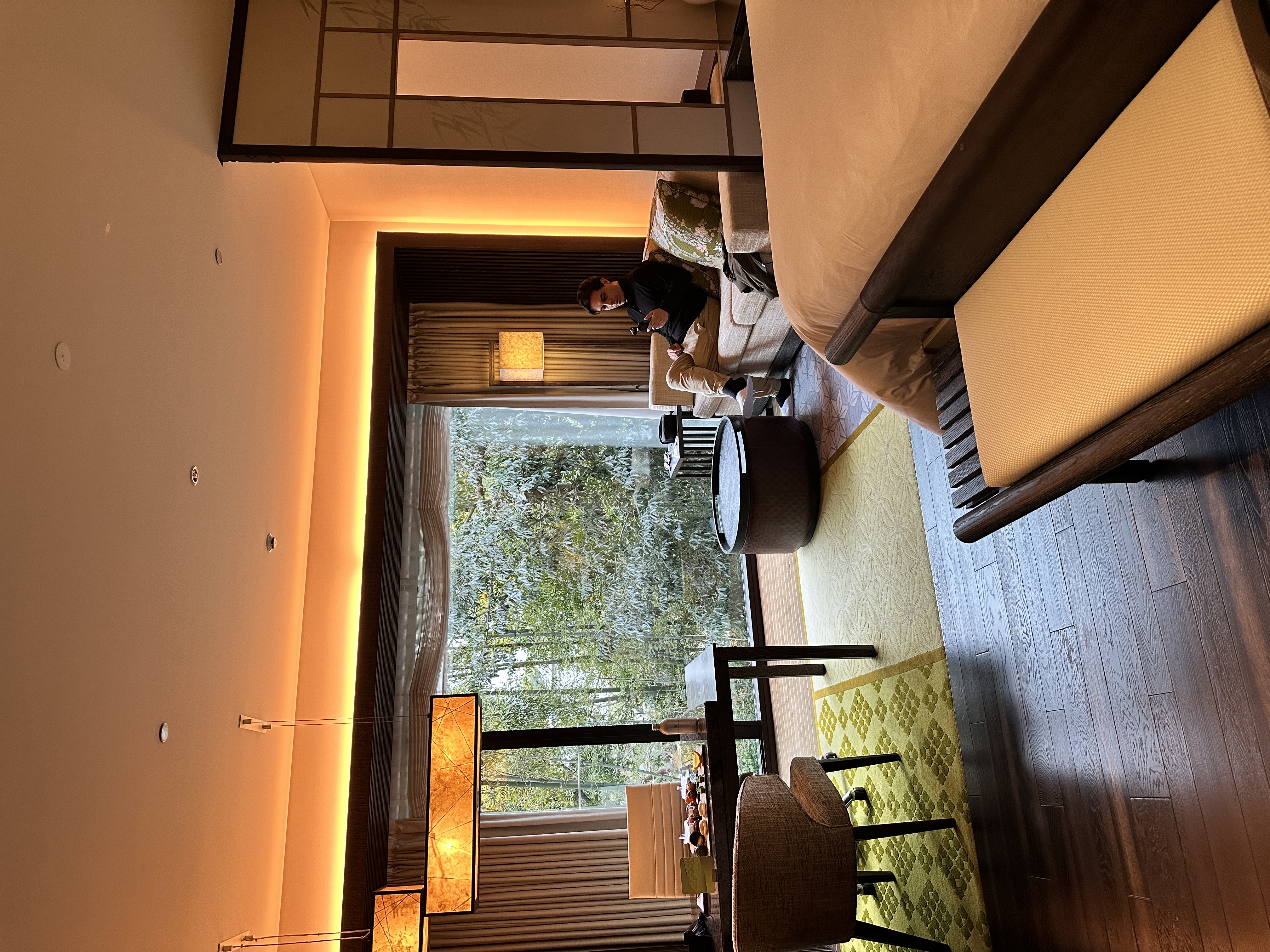 Man sitting on a couch of the Four Seasons Premiere Garden Heritage Room with views of the garden.