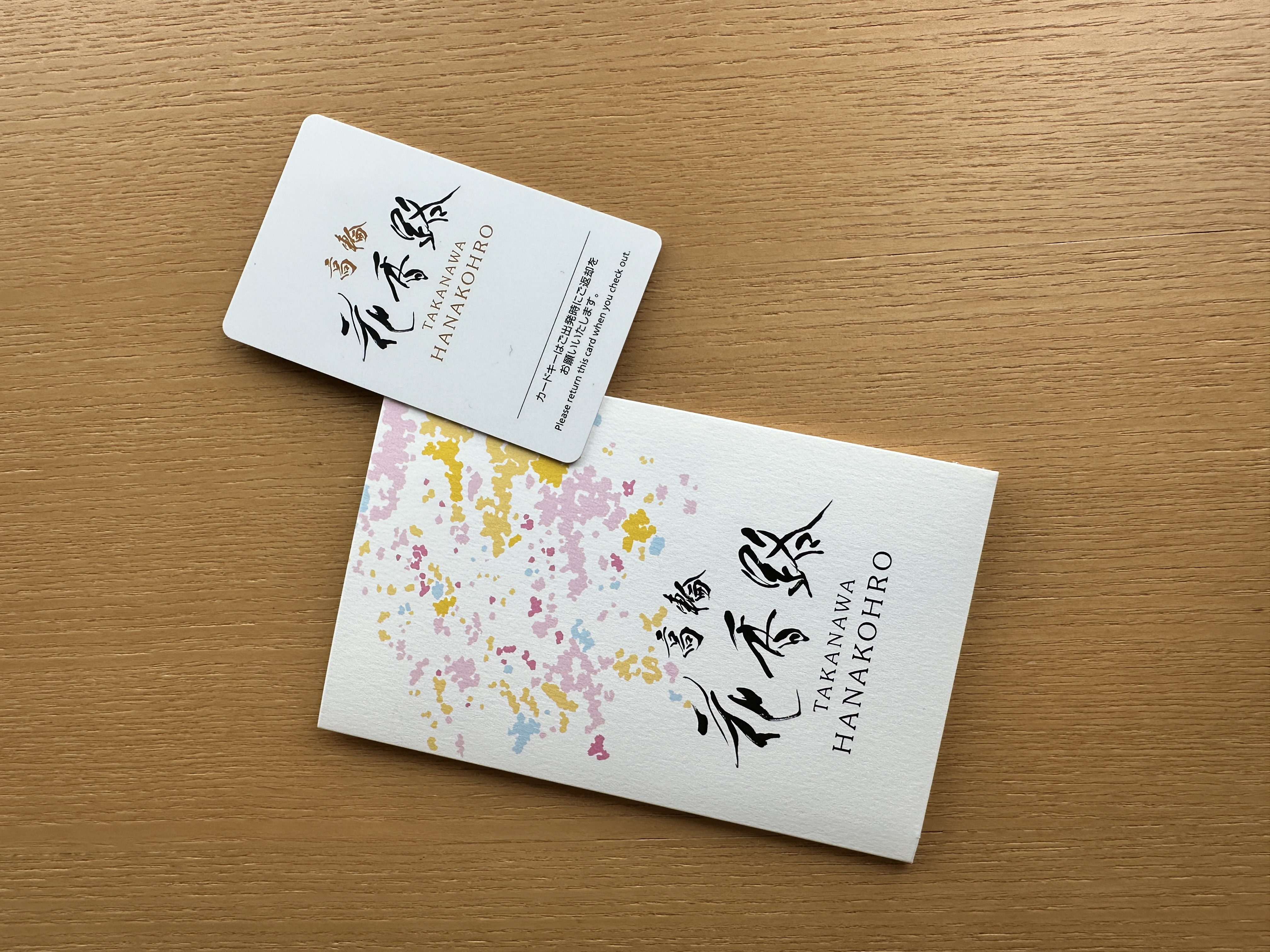 Takanawa Hanakohro room key card and floral key folder on a wooden table.