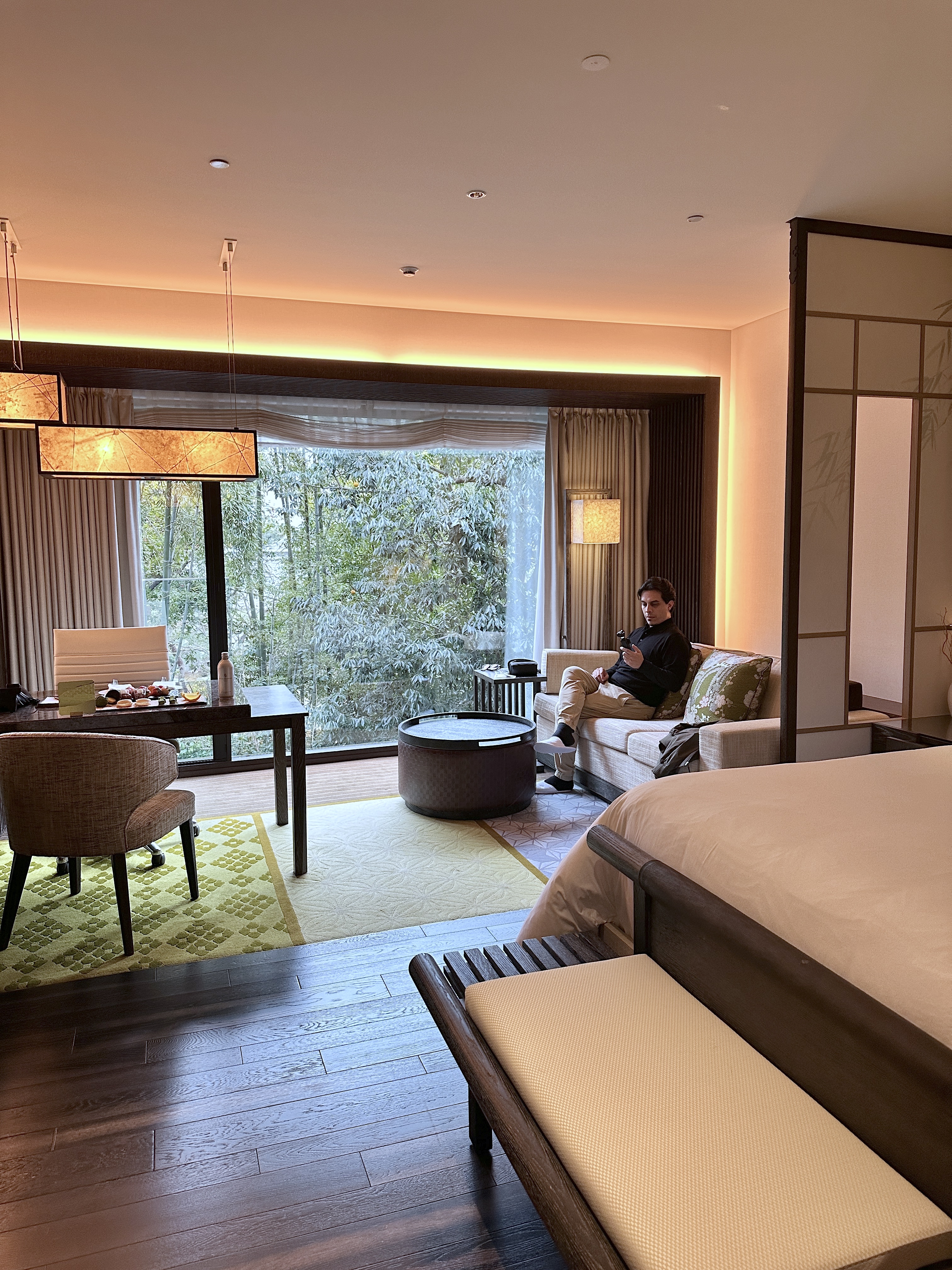 Man sitting on a couch of the Four Seasons Premiere Garden Heritage Room with views of the garden.
