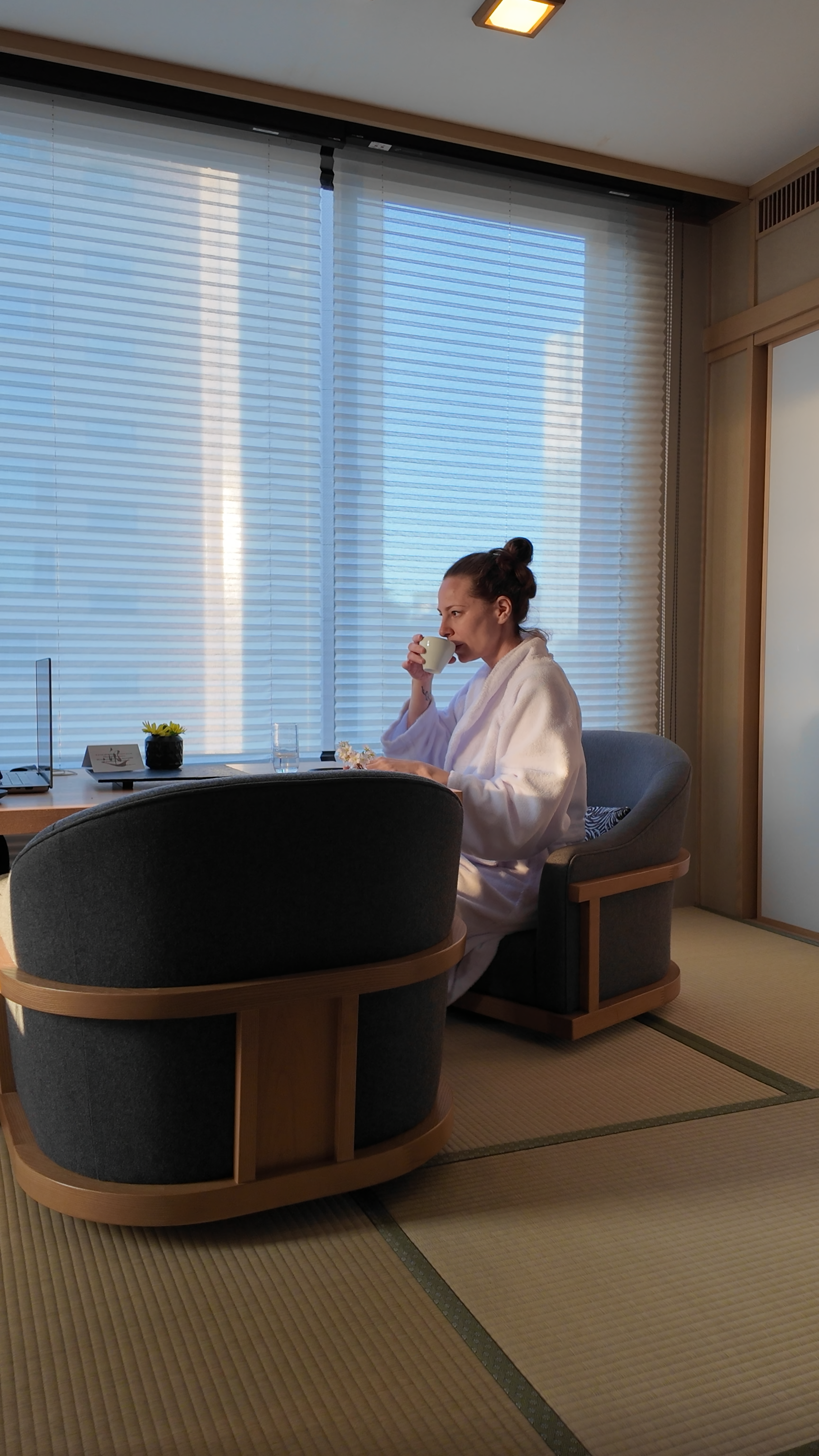 Krystal Ariel in a robe drinking coffee in the tatami dining nook of a Takanawa Hanakohro suite in Tokyo.