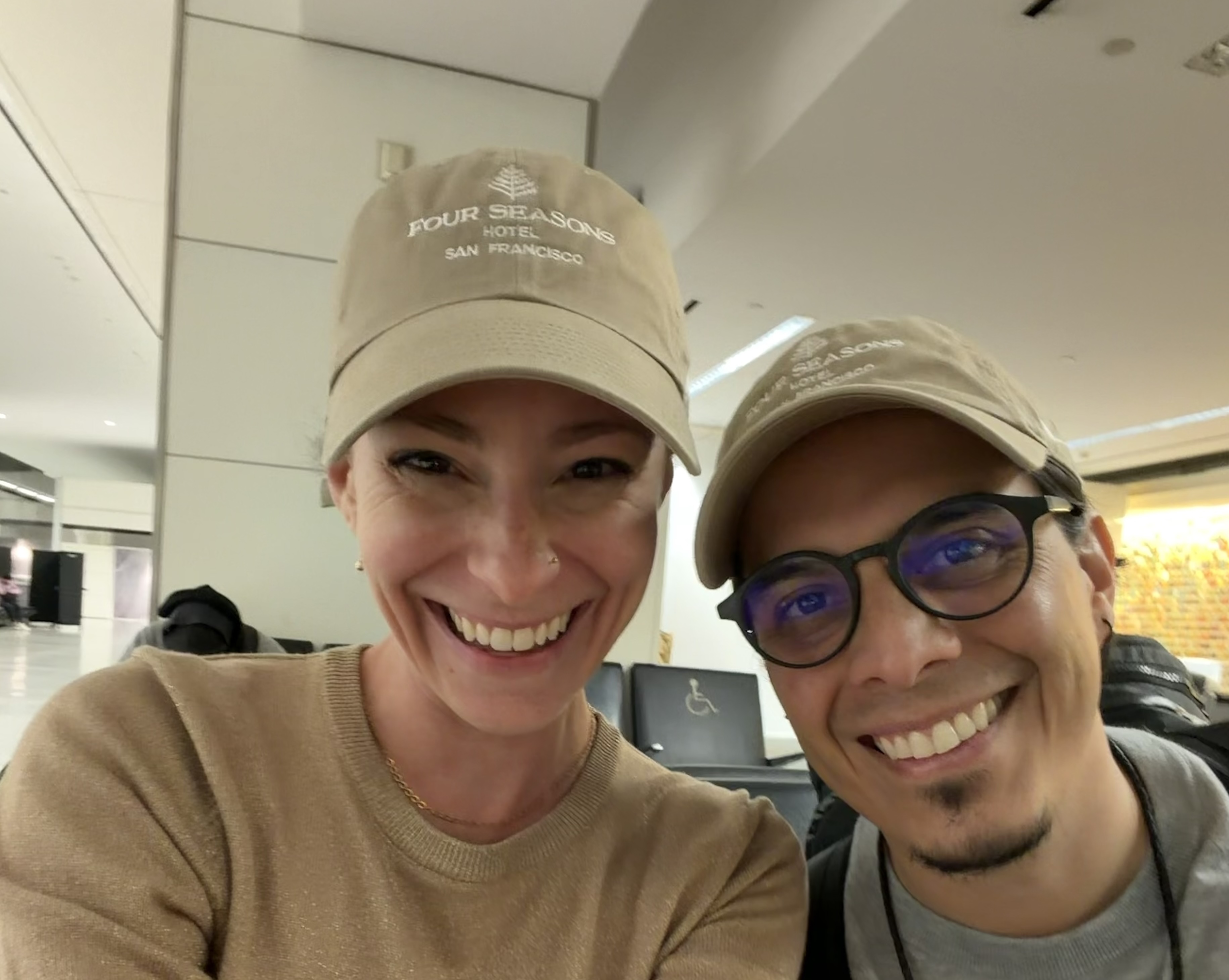 Krystal Ariel and Israel Pasos wearing matching Four Seasons Hotel San Francisco caps.