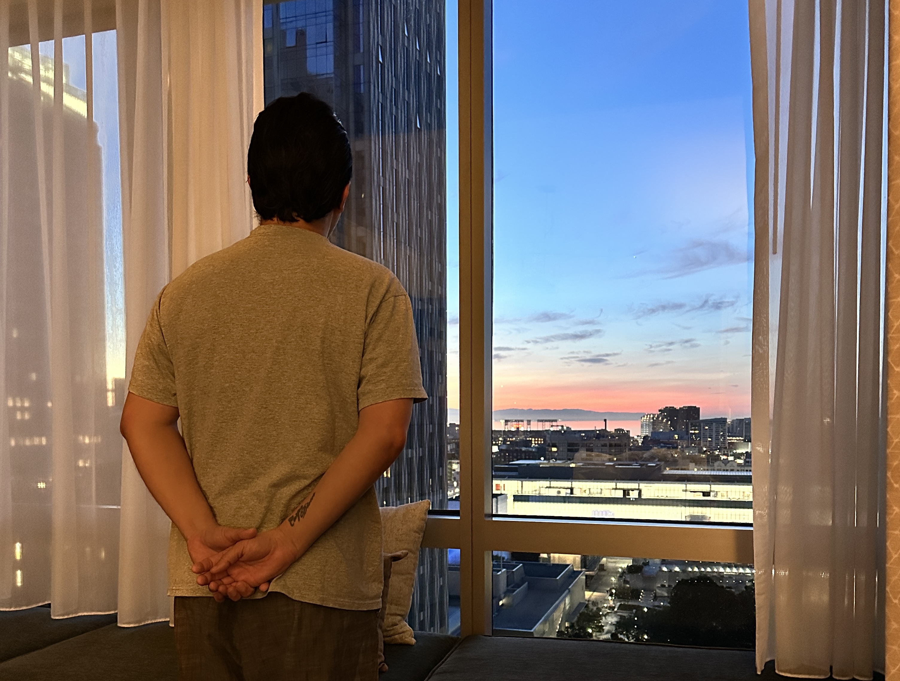 Israel Pasos standing in front of the window with San Francisco city views at Four Seasons San Francisco.